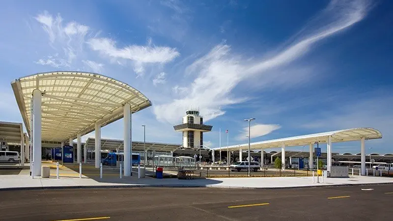 Exterior entrance and passenger pickup area at Oakland International Airport (OAK) with modern terminal structure and roadway.
